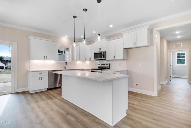157 Gumtop Dr, Zebulon, NC 27597 - kitchen featuring appliances with stainless steel finishes, white cabinetry, ornamental molding, decorative backsplash, and a kitchen island