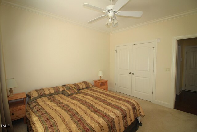 carpeted bedroom featuring ornamental molding, a closet, and a ceiling fan