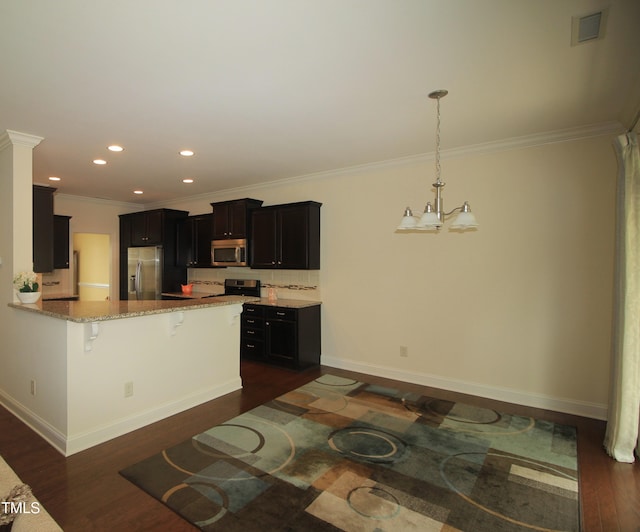 kitchen featuring stainless steel appliances, a kitchen breakfast bar, a chandelier, light stone countertops, and dark wood-style floors