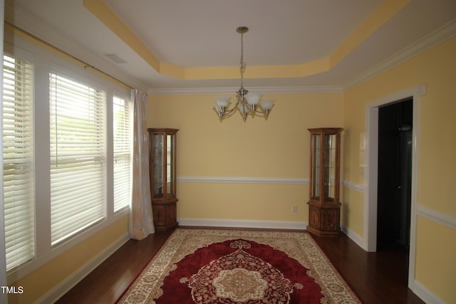 unfurnished dining area with a chandelier, wood finished floors, a tray ceiling, and baseboards