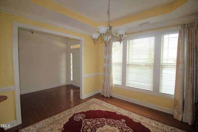 unfurnished dining area featuring a chandelier, wood finished floors, plenty of natural light, and a raised ceiling