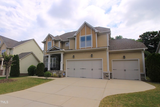 craftsman inspired home with stone siding, driveway, a front yard, and an attached garage