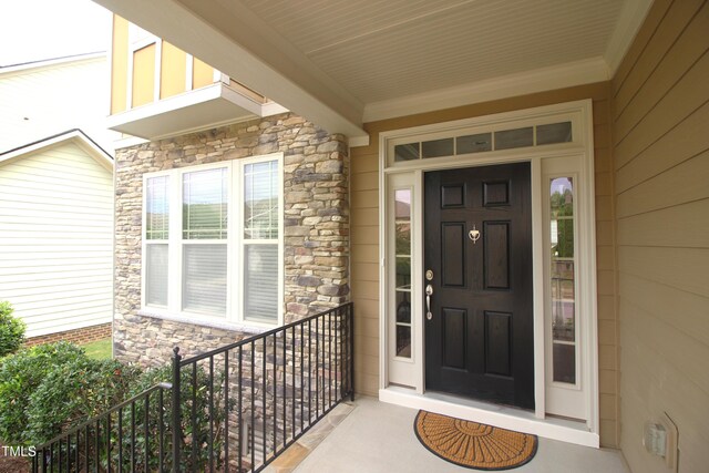 doorway to property with stone siding and a porch