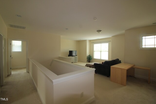 corridor with light colored carpet, healthy amount of natural light, baseboards, and an upstairs landing