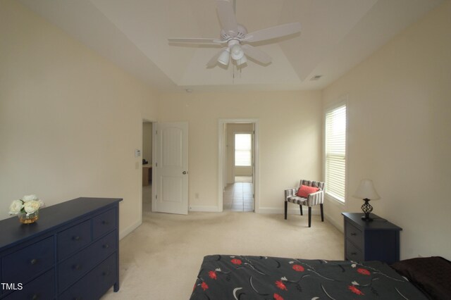 bedroom with light colored carpet, a tray ceiling, baseboards, and ceiling fan