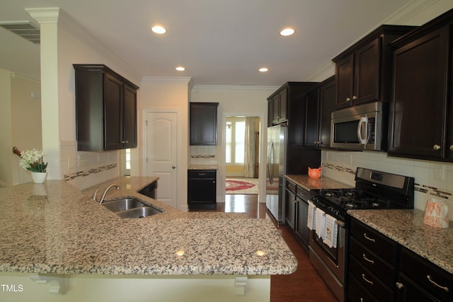 kitchen with stainless steel appliances, a sink, light stone counters, decorative backsplash, and a peninsula