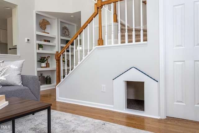 staircase with wood finished floors and built in shelves