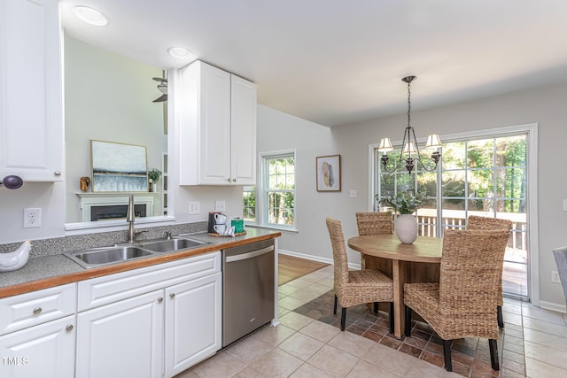 kitchen with stainless steel dishwasher, a sink, a chandelier, white cabinets, and hanging light fixtures