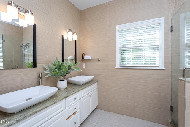 bathroom featuring tile walls, a stall shower, double vanity, and backsplash