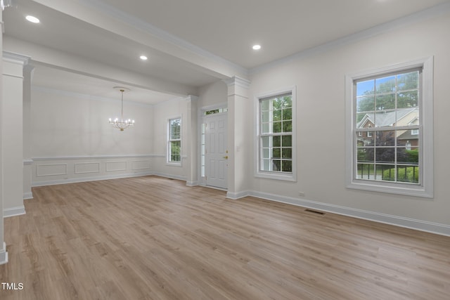 100 Citrus Pl, Cary, NC 27519 - unfurnished room with crown molding, a chandelier, light wood-type flooring, a decorative wall, and ornate columns