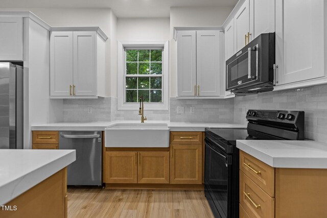 100 Citrus Pl, Cary, NC 27519 - kitchen featuring appliances with stainless steel finishes, a sink, light wood-type flooring, light countertops, and backsplash