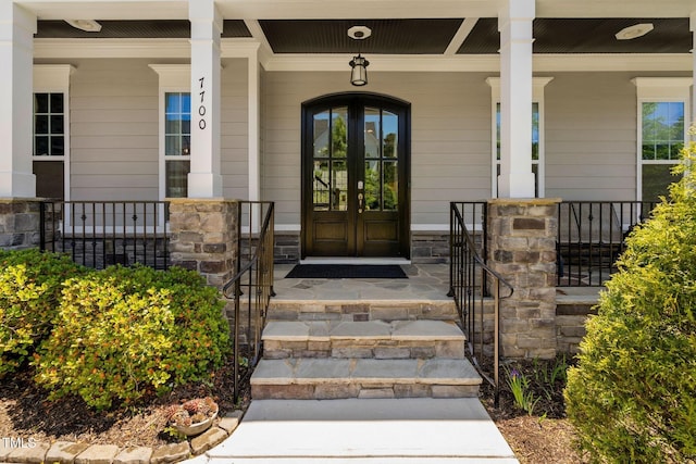 doorway to property with a porch, french doors, and stone siding