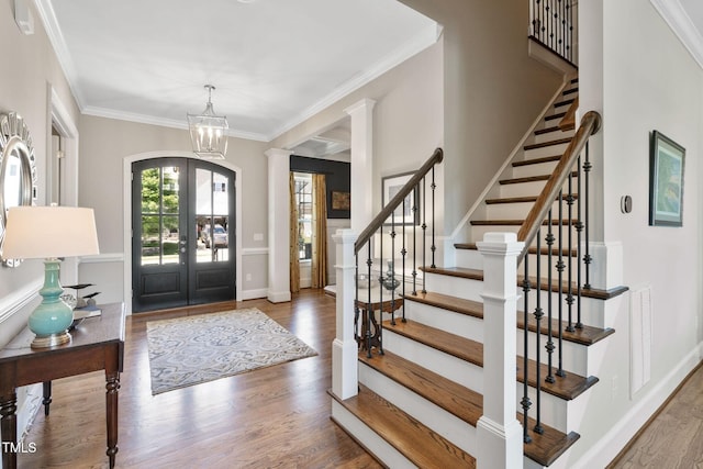 entryway featuring french doors, a chandelier, stairway, wood finished floors, and crown molding