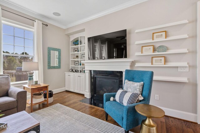 living room featuring crown molding, baseboards, a fireplace with flush hearth, dark wood-style flooring, and built in features