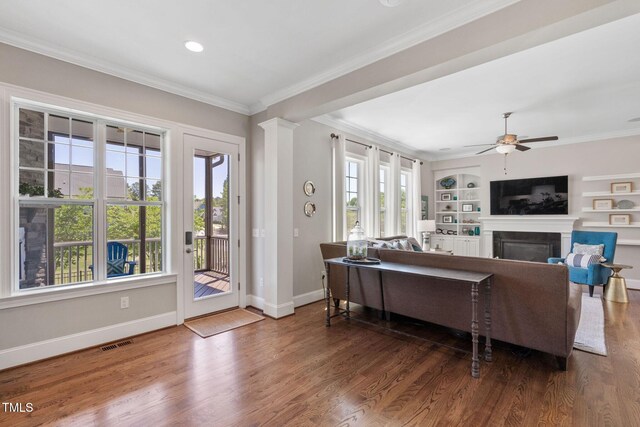 living area with a fireplace, healthy amount of natural light, baseboards, ornamental molding, and recessed lighting