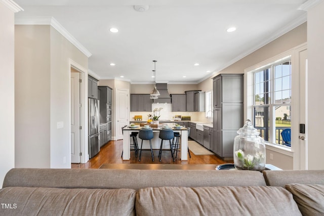living room with wood finished floors, recessed lighting, and ornamental molding