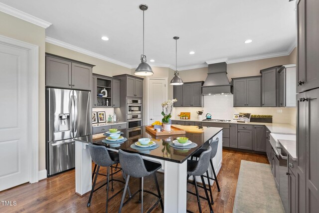 kitchen with appliances with stainless steel finishes, custom exhaust hood, a center island, gray cabinets, and tasteful backsplash