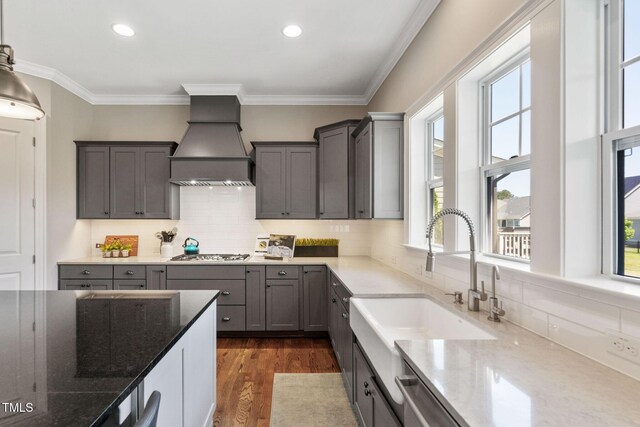 kitchen with custom exhaust hood, a sink, stainless steel appliances, stone counters, and backsplash