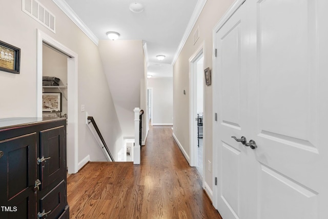 hall featuring an upstairs landing, wood finished floors, crown molding, and baseboards