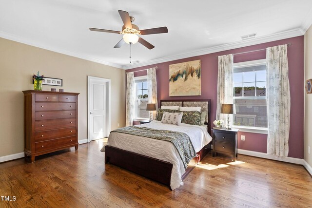 bedroom with wood finished floors, crown molding, baseboards, and a ceiling fan