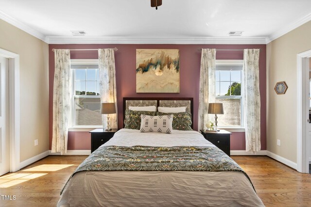bedroom with multiple windows, wood finished floors, baseboards, and crown molding
