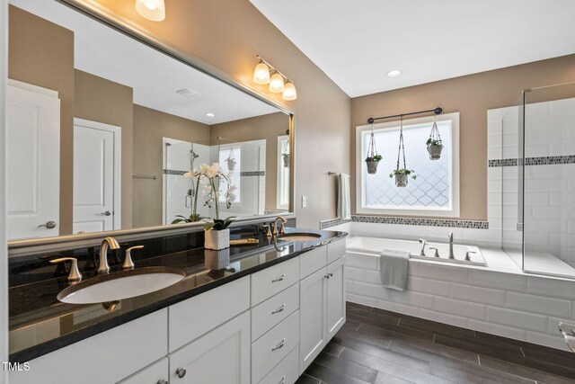 full bathroom featuring a shower stall, a garden tub, double vanity, and wood finished floors