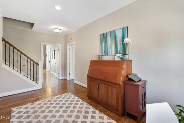 foyer featuring wood finished floors, baseboards, stairs, and recessed lighting