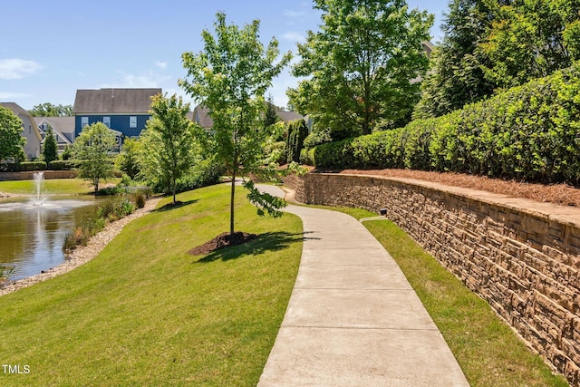 surrounding community with a water view and a lawn