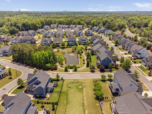 aerial perspective of suburban area featuring a nearby body of water and a forest