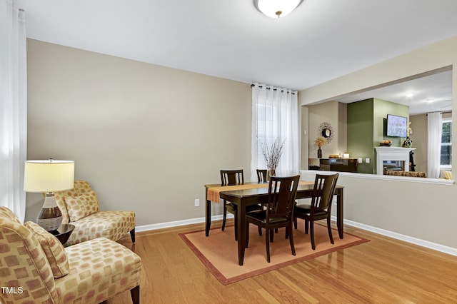 1141 Brookhill Way, Cary, NC 27519 - dining space with light wood-style flooring, baseboards, and a glass covered fireplace