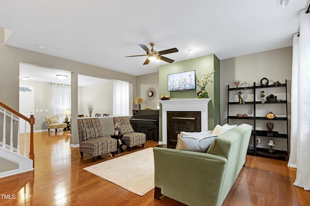 1141 Brookhill Way, Cary, NC 27519 - living area featuring stairway, ceiling fan, a glass covered fireplace, wood finished floors, and baseboards