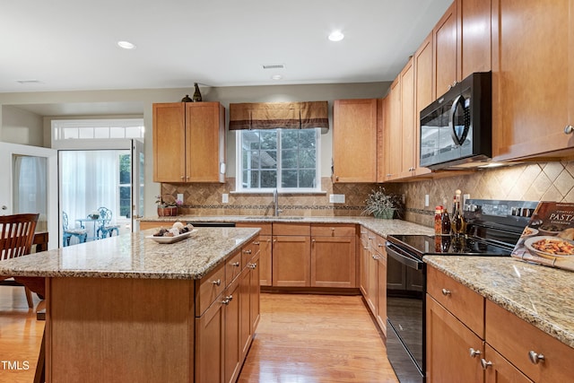 1141 Brookhill Way, Cary, NC 27519 - kitchen with black appliances, light wood finished floors, light stone counters, a kitchen island, and a sink