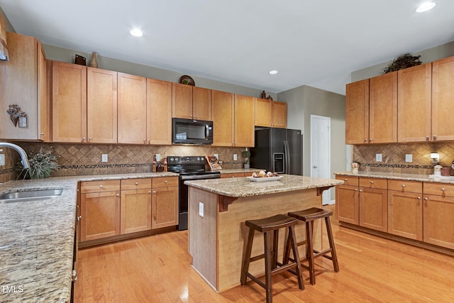 1141 Brookhill Way, Cary, NC 27519 - kitchen featuring black appliances, a sink, light wood finished floors, tasteful backsplash, and a breakfast bar area