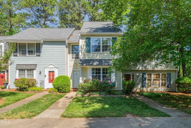 multi unit property with a front yard and roof with shingles