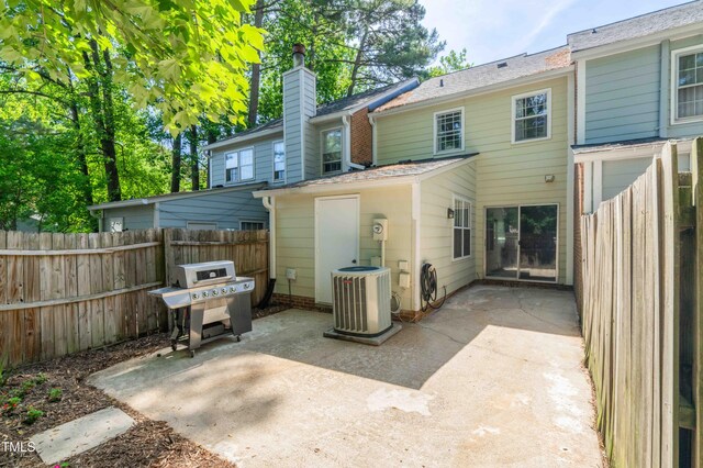 rear view of property with central air condition unit, a patio area, fence, and a chimney