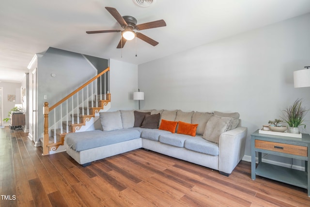 living area with ceiling fan, wood finished floors, and stairway