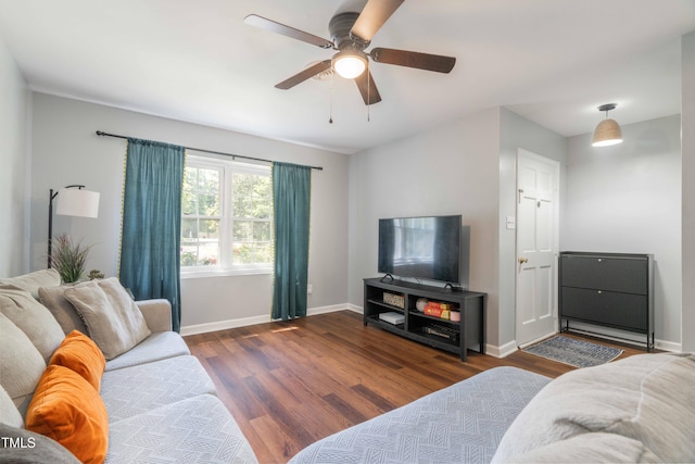 living area with wood finished floors, a ceiling fan, and baseboards
