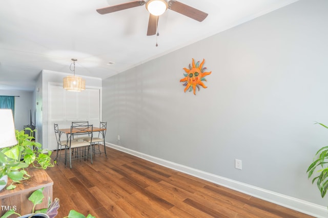 dining space featuring wood finished floors, baseboards, ceiling fan, and crown molding