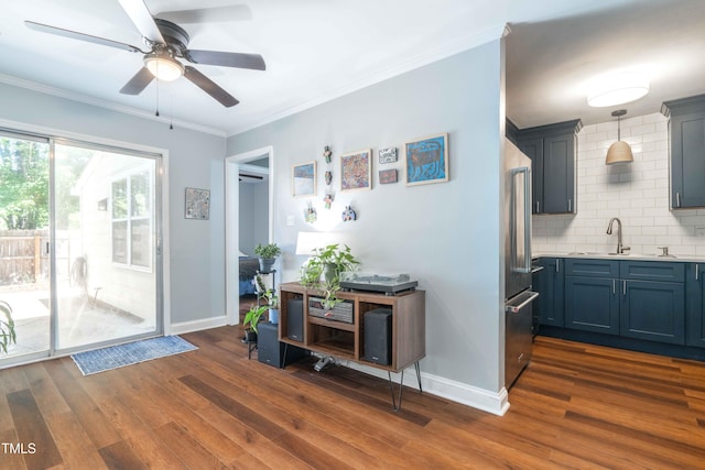 doorway to outside with a sink, baseboards, dark wood-style flooring, a ceiling fan, and crown molding