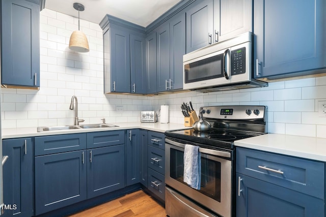 kitchen with stainless steel appliances, a sink, and blue cabinets