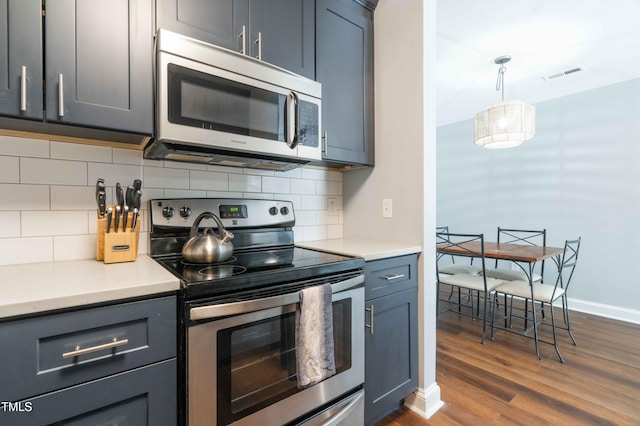 kitchen featuring stainless steel appliances, dark wood-type flooring, tasteful backsplash, and light countertops