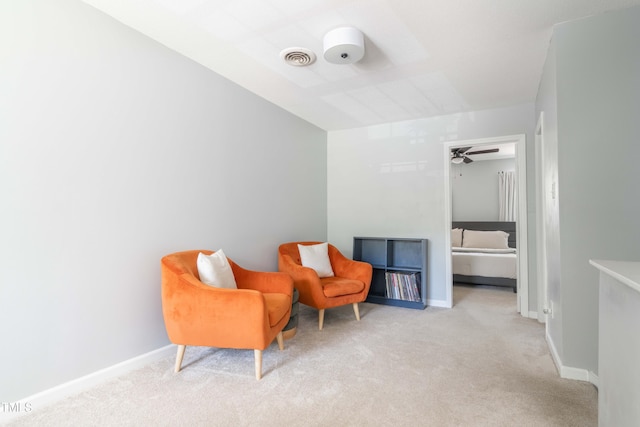sitting room featuring carpet, baseboards, and ceiling fan