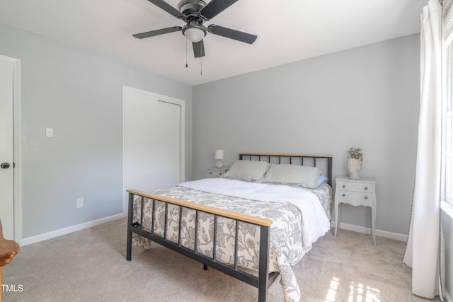 bedroom featuring light colored carpet, baseboards, a closet, and a ceiling fan