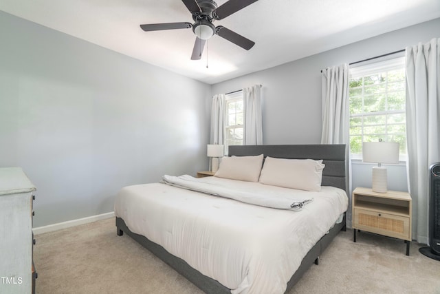bedroom with light carpet, multiple windows, and ceiling fan