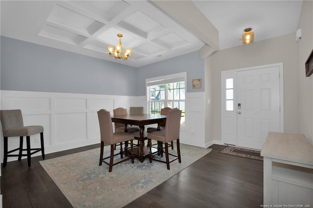 dining space featuring an inviting chandelier, coffered ceiling, a decorative wall, dark wood-style flooring, and beamed ceiling