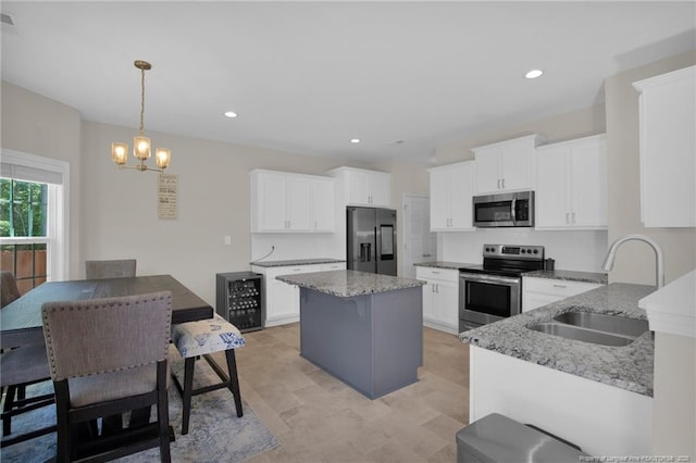 kitchen with an inviting chandelier, a sink, light stone countertops, appliances with stainless steel finishes, and wine cooler