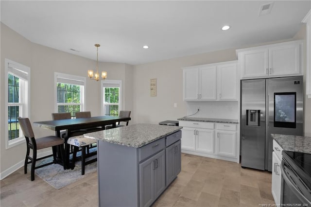 kitchen with light stone counters, an inviting chandelier, white cabinetry, stainless steel fridge with ice dispenser, and a kitchen island