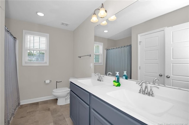 full bath with toilet, visible vents, baseboards, and a sink