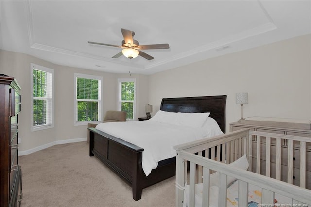 bedroom with light carpet, a raised ceiling, baseboards, and a ceiling fan