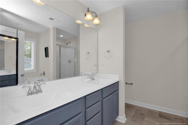 full bath featuring a stall shower, baseboards, double vanity, and a sink